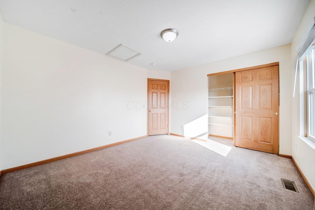 unfurnished bedroom with a closet, carpet, visible vents, and baseboards