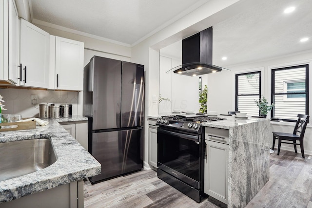 kitchen with white cabinetry, range with gas cooktop, light stone countertops, stainless steel fridge, and island exhaust hood