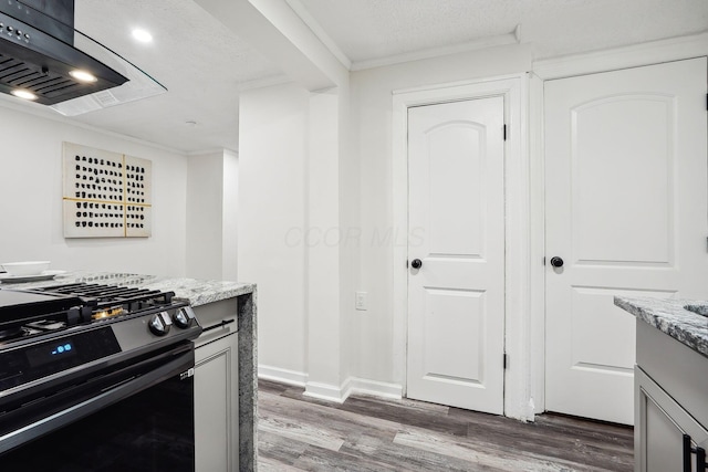 kitchen featuring dark wood-type flooring, gas range, light stone countertops, and extractor fan