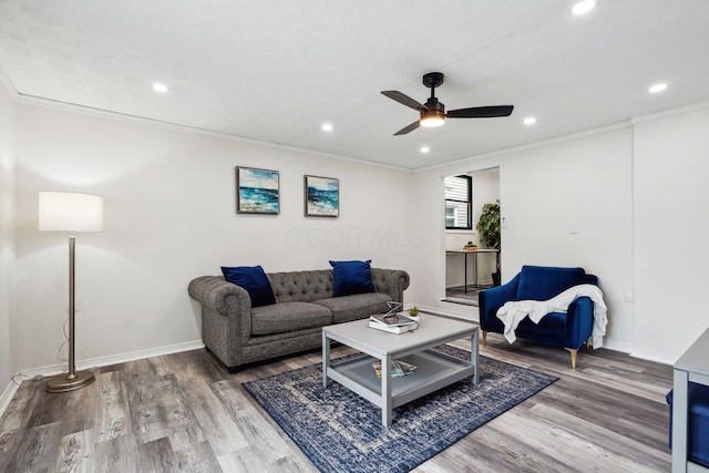 living room featuring ceiling fan, wood-type flooring, a textured ceiling, and ornamental molding