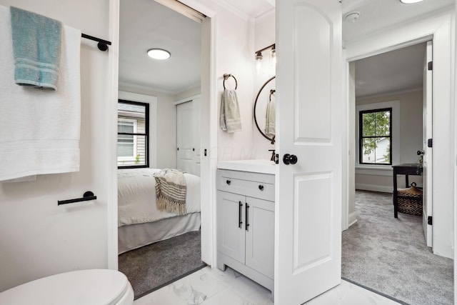 bathroom with toilet, vanity, and crown molding