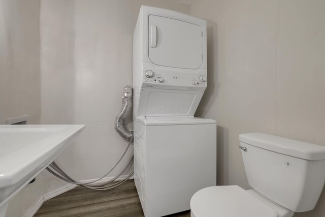 washroom with a sink, laundry area, stacked washing maching and dryer, and wood finished floors