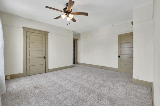 unfurnished room featuring light carpet, baseboards, and a ceiling fan