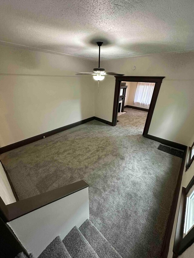 interior space featuring carpet, visible vents, baseboards, and a textured ceiling