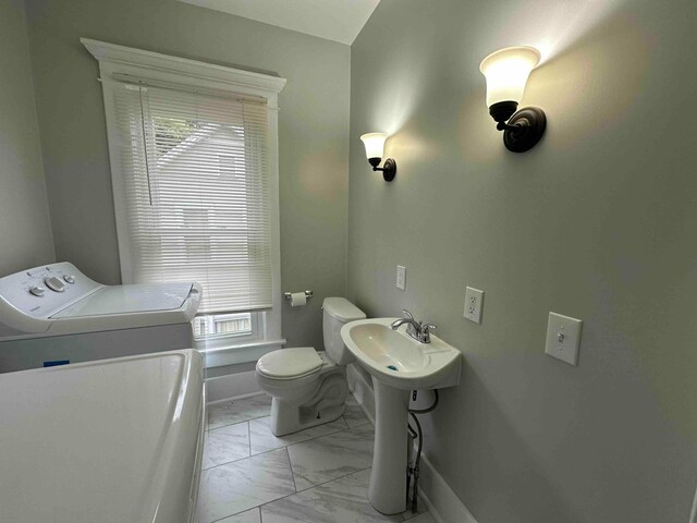 bathroom with washer / dryer, marble finish floor, baseboards, and toilet