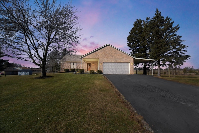 view of front facade featuring aphalt driveway, an attached carport, a lawn, and a garage