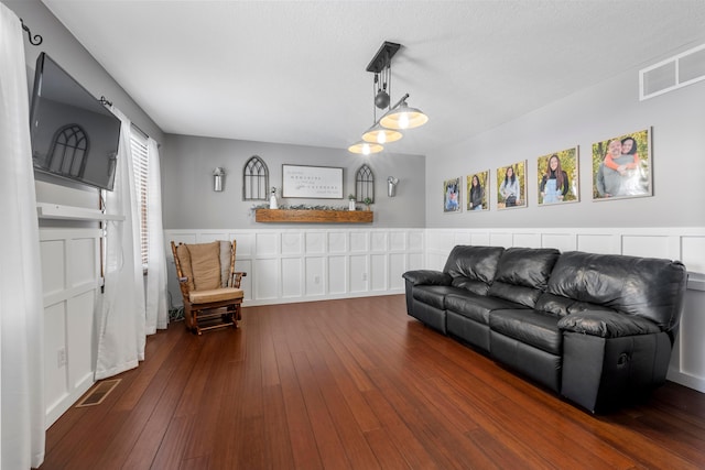 living area featuring visible vents, wainscoting, and hardwood / wood-style floors