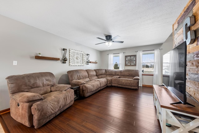 living room with dark wood finished floors, baseboards, ceiling fan, and a textured ceiling