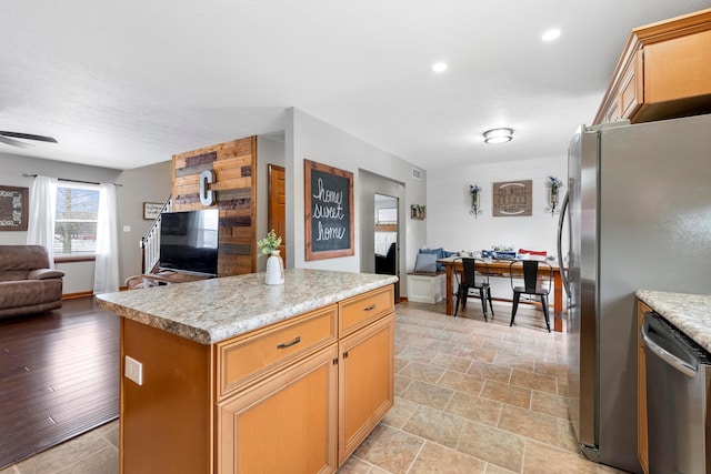 kitchen featuring light countertops, a ceiling fan, a center island, open floor plan, and stainless steel appliances
