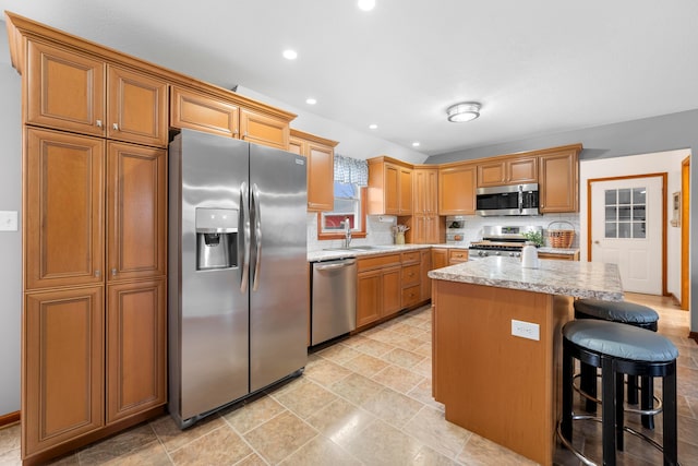 kitchen with a sink, a kitchen bar, appliances with stainless steel finishes, a center island, and recessed lighting