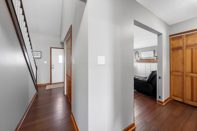 hallway with dark wood-style floors, baseboards, and stairway