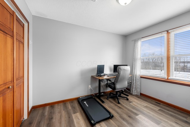office space featuring visible vents, baseboards, and wood finished floors