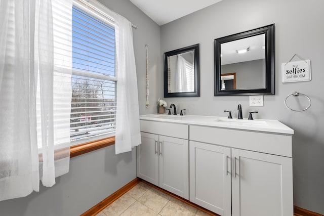 bathroom with tile patterned floors, a sink, double vanity, and baseboards