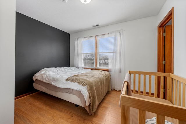 bedroom with light wood finished floors and visible vents