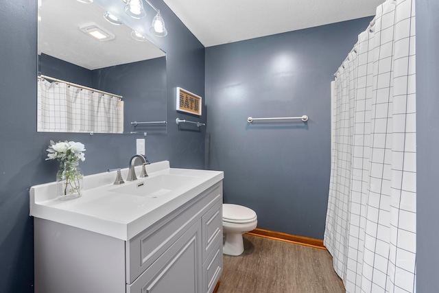 bathroom featuring a shower with curtain, vanity, toilet, baseboards, and wood finished floors