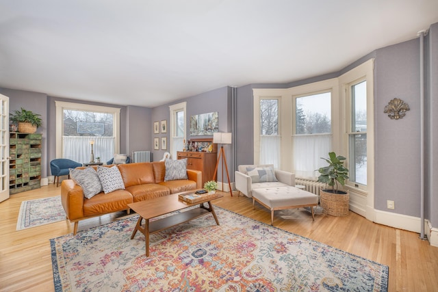 living room featuring light wood-style floors, radiator, and baseboards