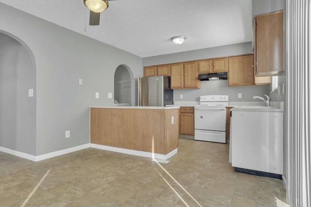 kitchen with arched walkways, white range with electric stovetop, light countertops, freestanding refrigerator, and a sink