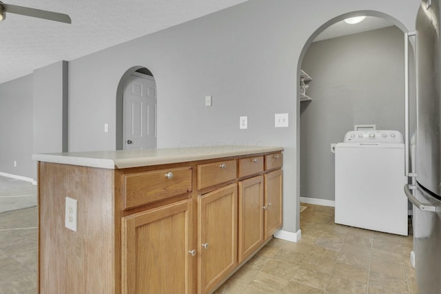 kitchen featuring light countertops, ceiling fan, a textured ceiling, washer / dryer, and baseboards