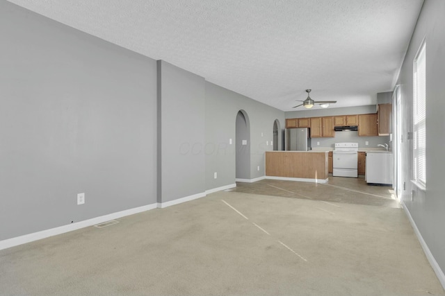 unfurnished living room featuring arched walkways, visible vents, a sink, a textured ceiling, and baseboards