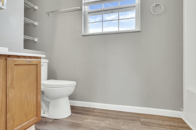 bathroom featuring baseboards, vanity, toilet, and wood finished floors