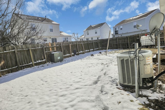 yard layered in snow featuring a fenced backyard, a residential view, and cooling unit