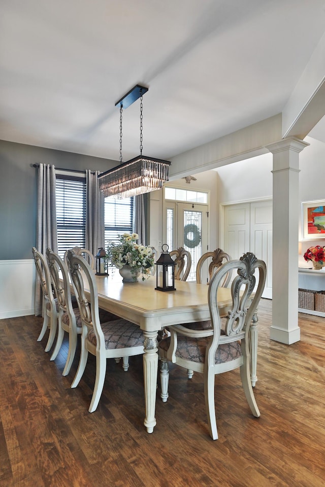 dining space with decorative columns and wood finished floors