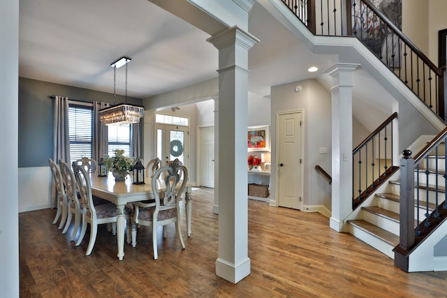 dining space featuring stairs, decorative columns, and wood finished floors