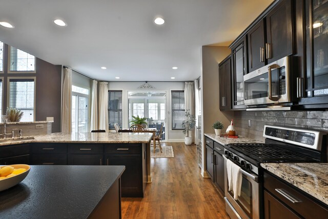 kitchen with recessed lighting, dark wood-type flooring, a sink, appliances with stainless steel finishes, and tasteful backsplash