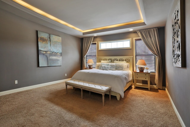 carpeted bedroom featuring baseboards and a tray ceiling