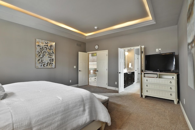 bedroom with carpet floors, a raised ceiling, visible vents, ensuite bathroom, and baseboards