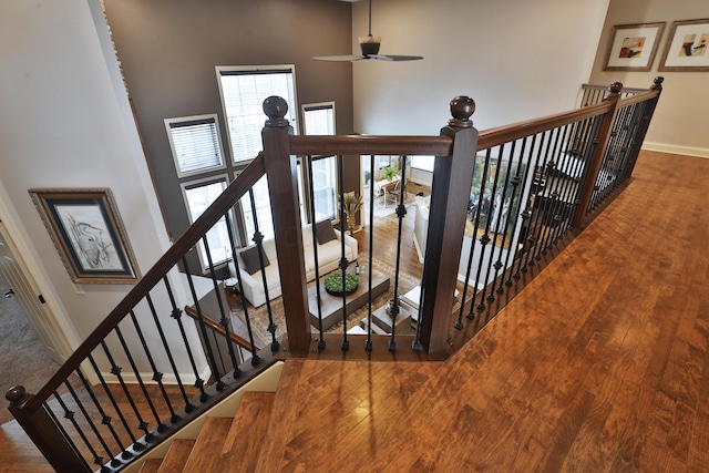 stairs with baseboards, a high ceiling, and wood finished floors