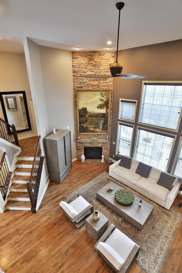 living area with baseboards, a fireplace, stairway, and wood finished floors