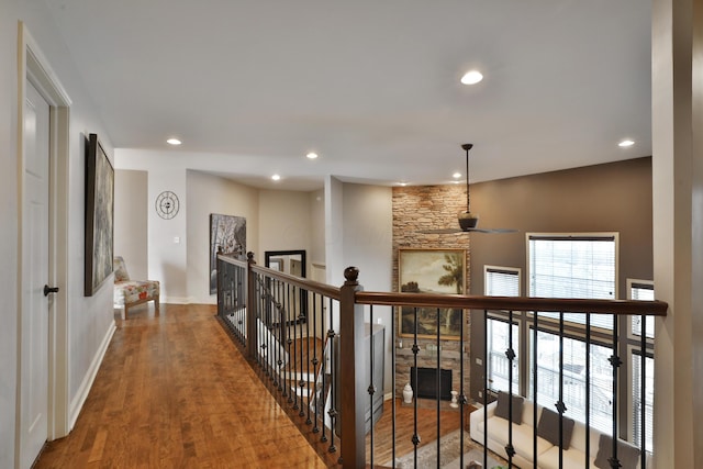 hallway featuring baseboards, wood finished floors, and recessed lighting