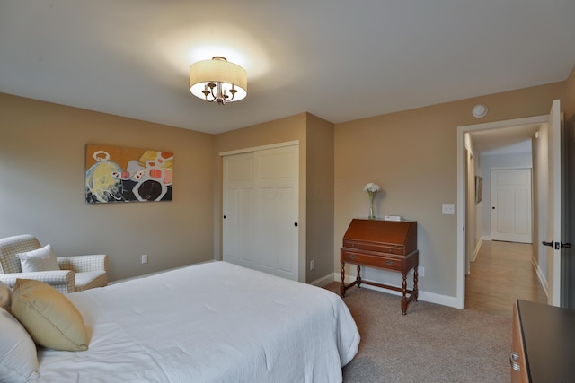 bedroom with baseboards, a closet, and light colored carpet