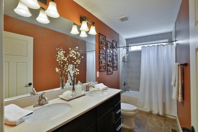 full bath with toilet, double vanity, visible vents, and a sink