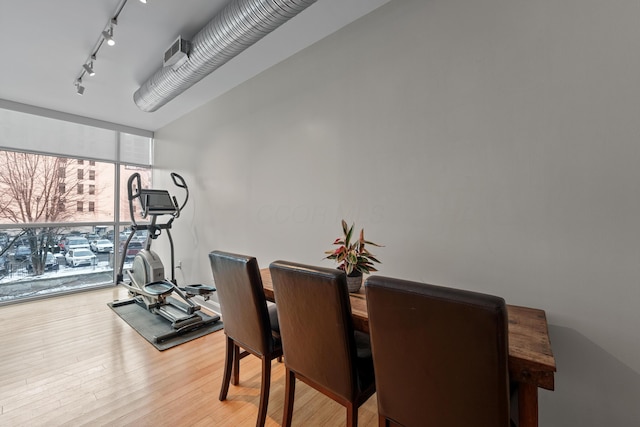 dining area with light wood-type flooring, rail lighting, and expansive windows