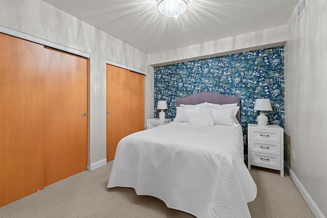 bedroom with baseboards, light colored carpet, and multiple closets