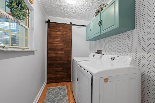 laundry area featuring cabinet space, a barn door, ornamental molding, light wood-style floors, and washing machine and dryer