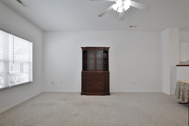 spare room with ceiling fan, carpet flooring, visible vents, and baseboards