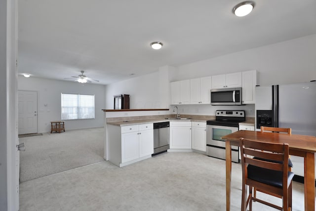 kitchen featuring white cabinetry, appliances with stainless steel finishes, open floor plan, and a sink