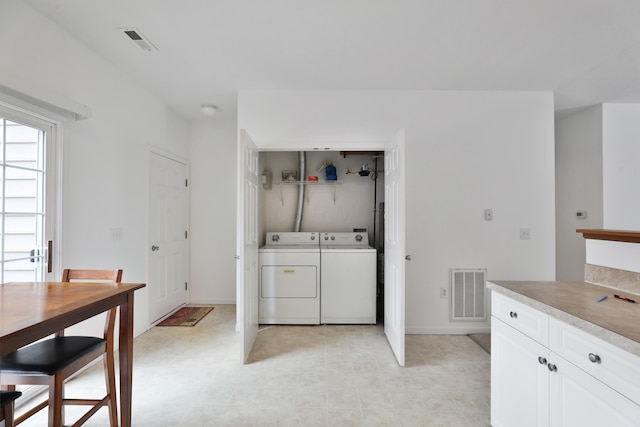 clothes washing area with laundry area, visible vents, and washing machine and clothes dryer