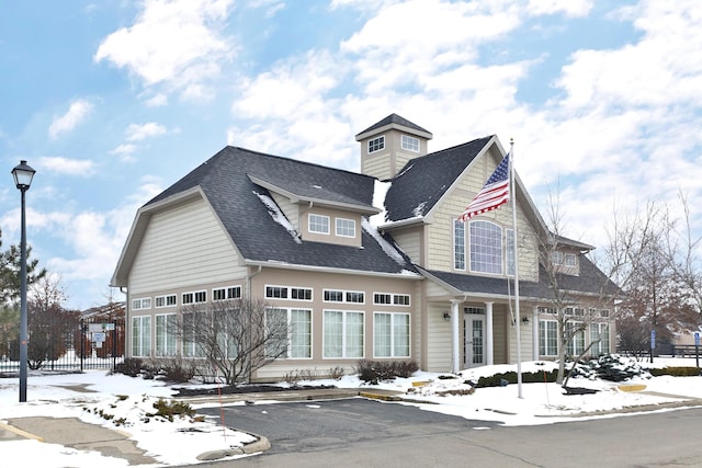 view of front facade with a shingled roof and fence