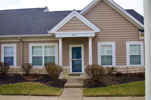 view of front of property with stone siding and roof with shingles