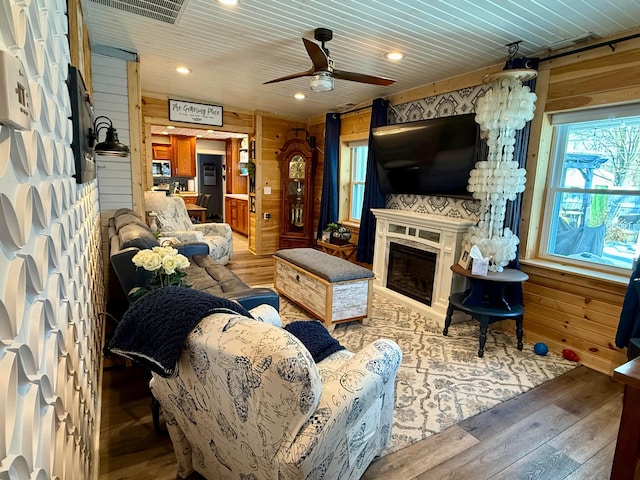 living room with a fireplace, wood-type flooring, visible vents, wood ceiling, and wooden walls