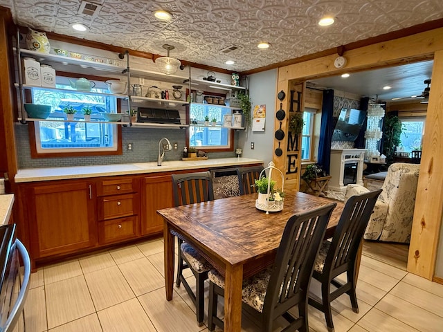 kitchen featuring a sink, light countertops, open shelves, brown cabinetry, and an ornate ceiling