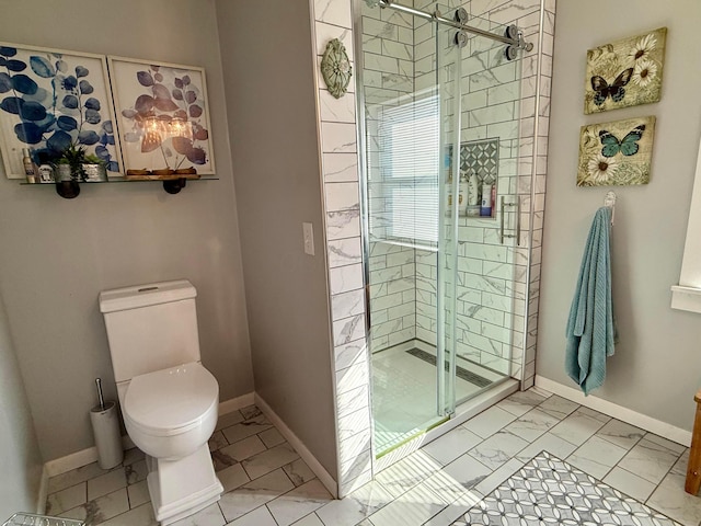 bathroom featuring marble finish floor, a stall shower, toilet, and baseboards