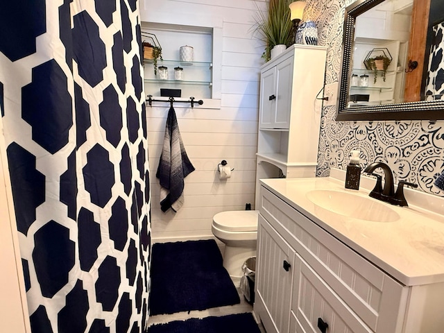 bathroom with toilet, wooden walls, a shower with shower curtain, and vanity