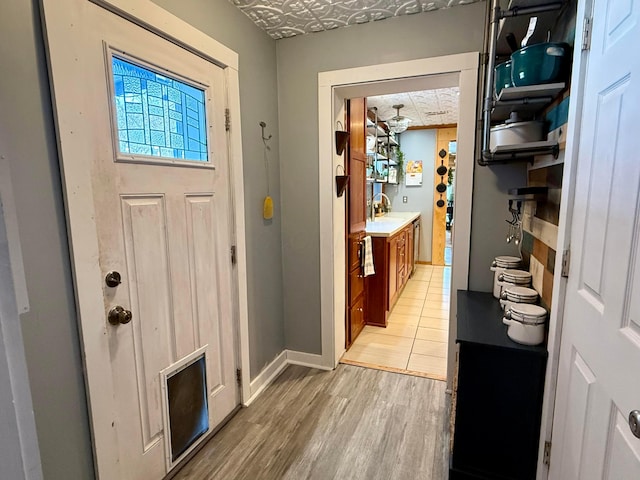 doorway to outside with light wood-style floors and baseboards