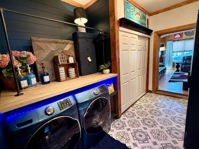 laundry area with crown molding, laundry area, wood walls, and separate washer and dryer