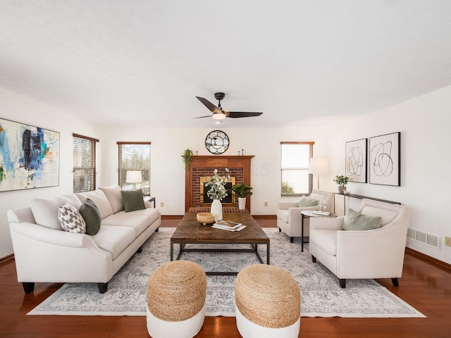 living room with a fireplace, wood finished floors, a ceiling fan, visible vents, and baseboards